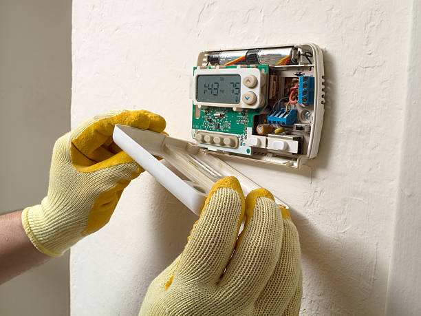 Air conditioning repair man performing maintenance Hispanic airconditioning repair man performing maintenance thermostat stock pictures, royalty-free photos & images