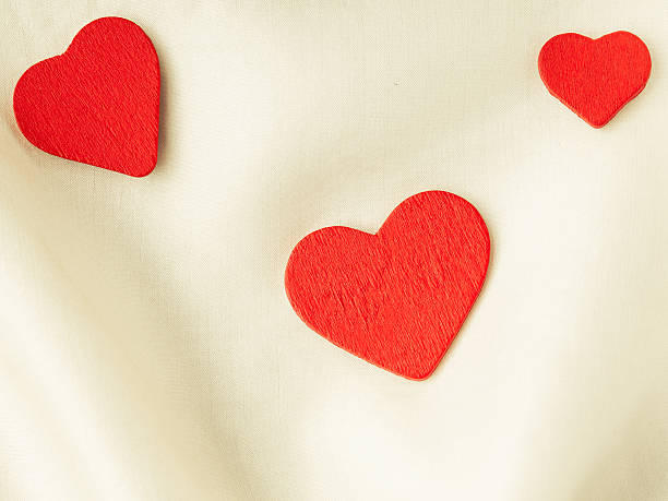 istock Red wooden decorative hearts on white silk background. 464080749