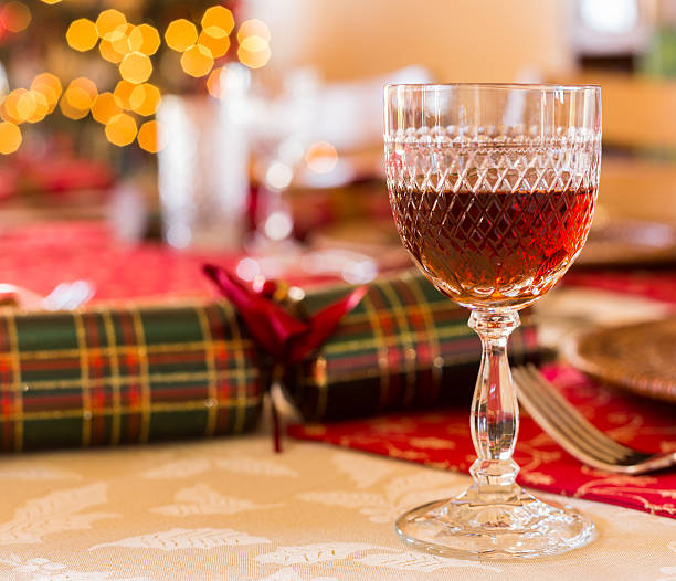 English Christmas table with sherry glass Christmas sherry in cut glass goblet on table set for Christmas lunch with crackers and decorated tree in background sherry stock pictures, royalty-free photos & images