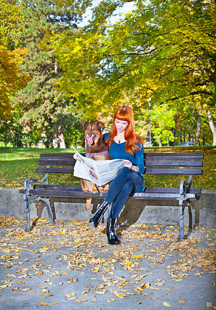 elegante mujer relajante con su perro en el parque big - newspaper dog pets grass fotografías e imágenes de stock