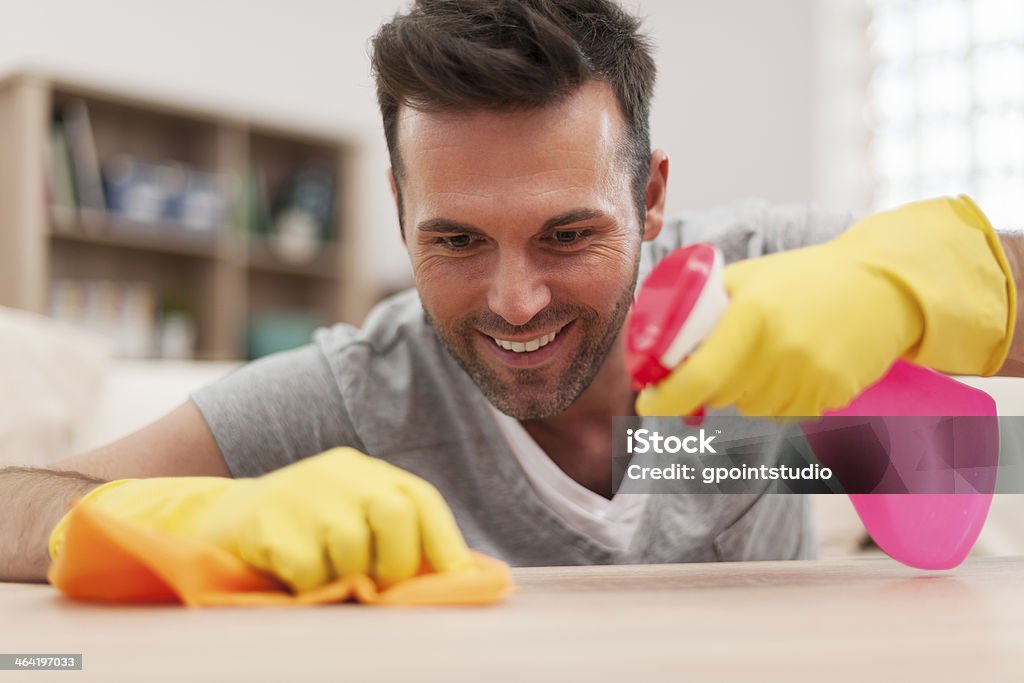 Smiling man cleaning desk in living room Adult Stock Photo