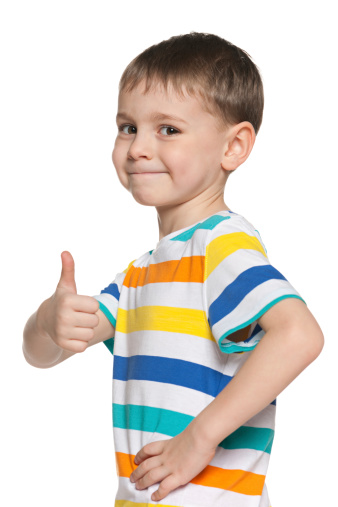 Cute boy holds his thumb up on the white background