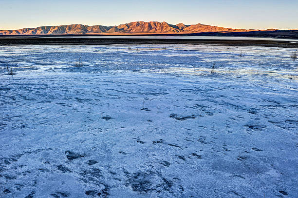 istock Frozen lake with grass and mountains in background 464218357