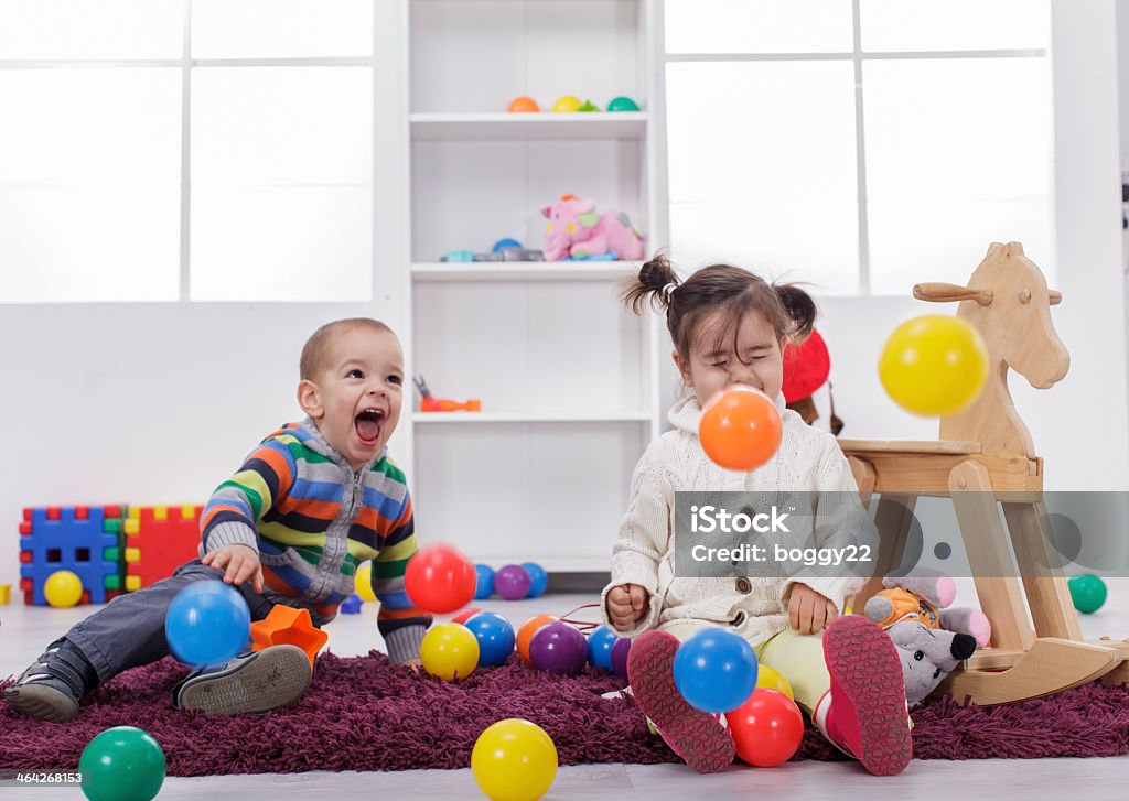 Boy and girl sitting down, playing with balls and laughing Kids playing in the room 2-3 Years Stock Photo