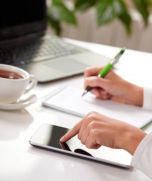 istock Woman hands with tablet PC and notepad at office 464272465