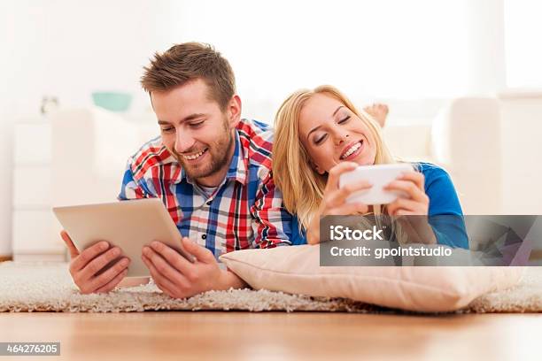 Happy Couple Spending Time With Electronic Equipment At Home Stock Photo - Download Image Now