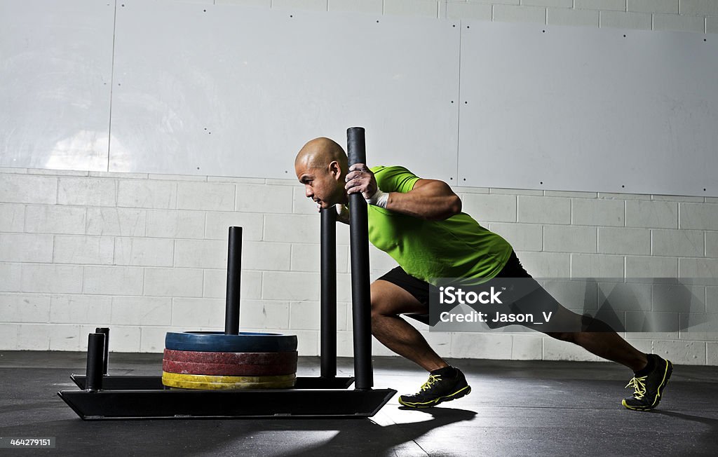 Athletic man pushing a gym sled A man pushing a weighted sled at a gym gym Sled Stock Photo