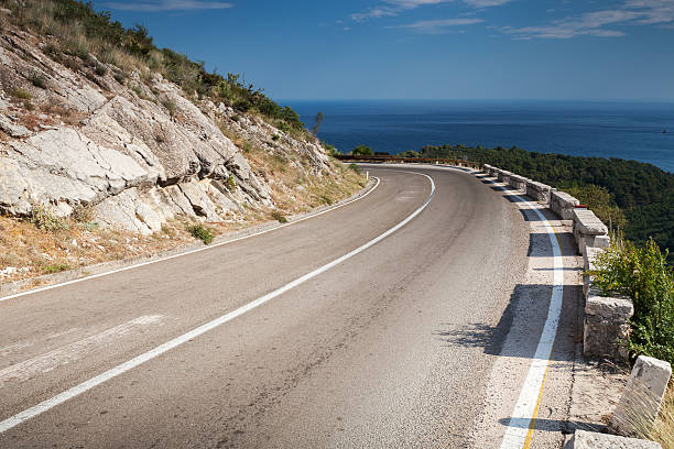 istock Left turn of mountain highway with blue sky and sea 464303339