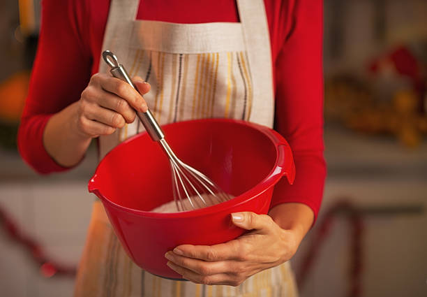 Closeup on young housewife using dough whisk