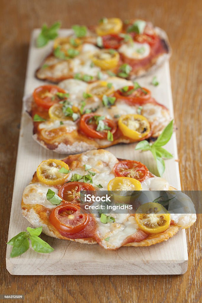 Mini pizzas with mozzarella, cherry tomatoes and basil Mini pizzas with mozzarella, colorful cherry tomatoes and basil.  Baked Stock Photo