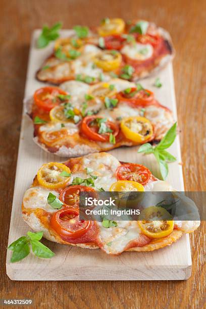 Mini Pizzas With Mozzarella Cherry Tomatoes And Basil Stock Photo - Download Image Now