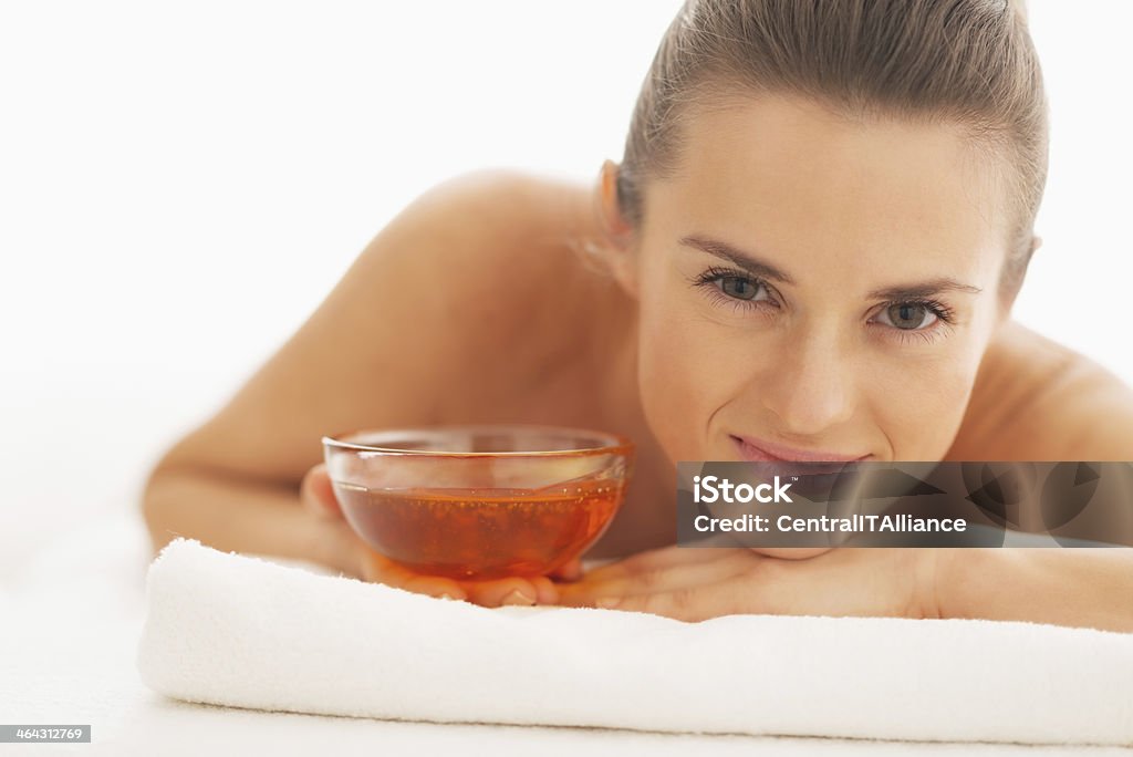Smiling woman laying on massage table with plate of honey Portrait of smiling young woman laying on massage table with plate of honey Adult Stock Photo
