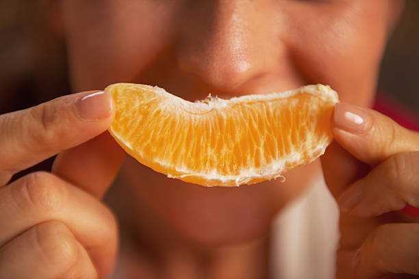 istock closeup on young woman making smile with orange slice 464317381