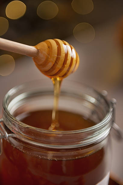 istock Closeup on honey flowing down from dipper in jar 464317437