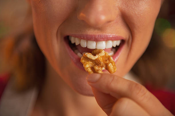 primer plano de joven ama de casa comiendo nueces - nuez fotografías e imágenes de stock