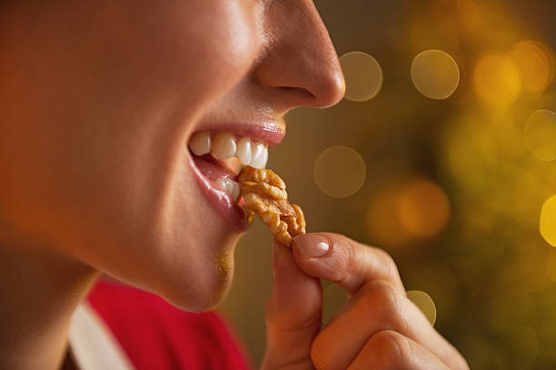 closeup on young housewife eating walnuts stock photo