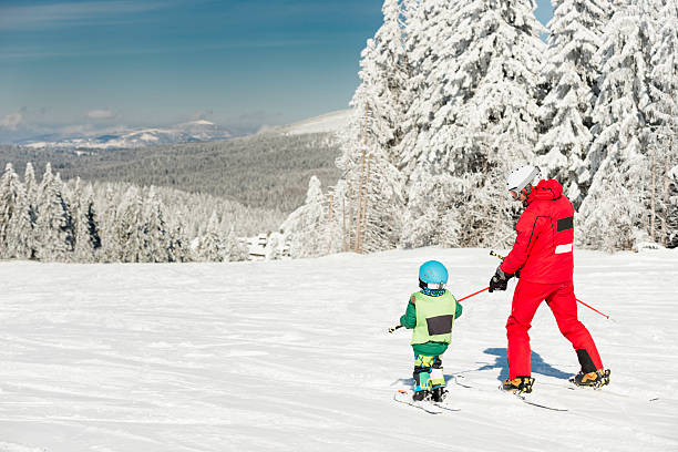 Ski lesson Little boy skiing downhill with ski instructor ski instructor stock pictures, royalty-free photos & images