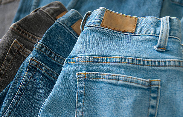 3 pairs of denim jeans lay on top of each other Image of three pairs of denim jeans shot with shallow depth of field. Useful image for any denim jean fashion theme with copy space in the leather tag. consumer confidence photos stock pictures, royalty-free photos & images