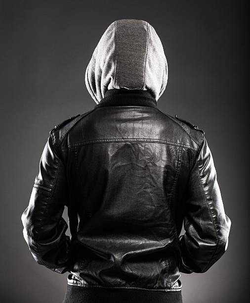 Young man in leather jacket and hood rear view Young man in leather jacket and hood rear view on back larrikin stock pictures, royalty-free photos & images