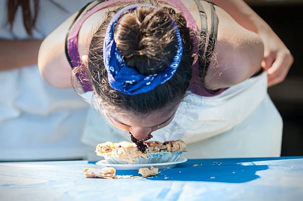 junge mädchen, die sich in kuchenesswettbewerb - wettessen stock-fotos und bilder