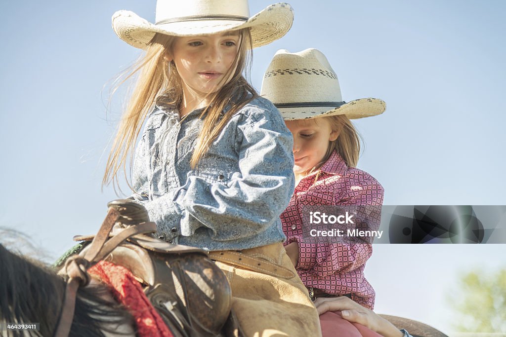 Cowgirls on Horseback Two little Cowgirls in Western-style Clothing and Cowboy Hat, riding together on the back of their Horse. Montana - Western USA Stock Photo