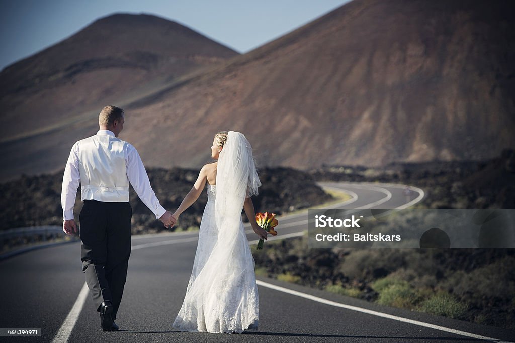 Bride and groom Newlyweds holding hands going down the road that winds uphill. 30-39 Years Stock Photo