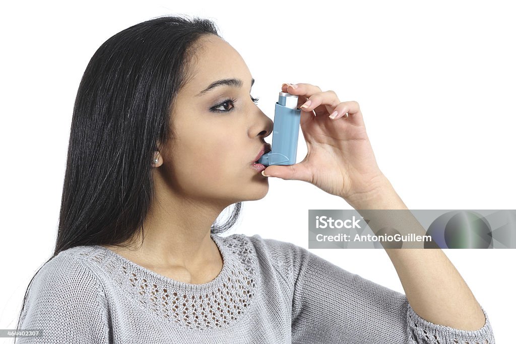 Asthmatic arab woman breathing from a inhaler Asthmatic arab woman breathing from a inhaler isolated on a white background Asthma Inhaler Stock Photo