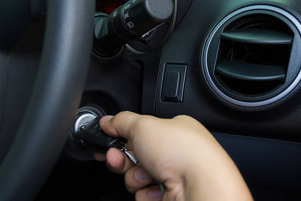 Mann drückt knopf am zündschlüssel mit wegfahrsperre auf dem hintergrund  des autos