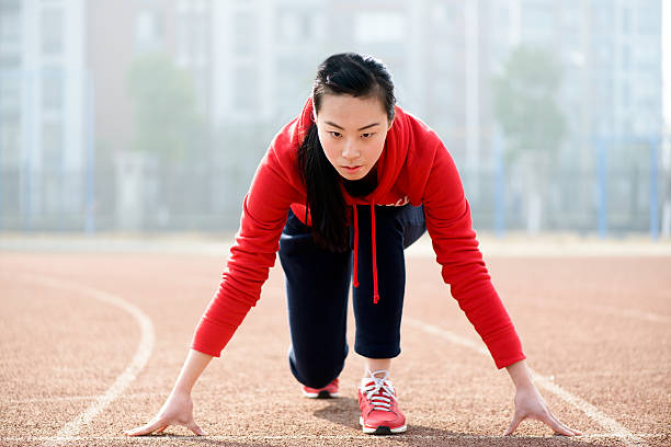 athletic asiatische frau in der ausgangsposition auf track - dividing line single line striped in a row stock-fotos und bilder