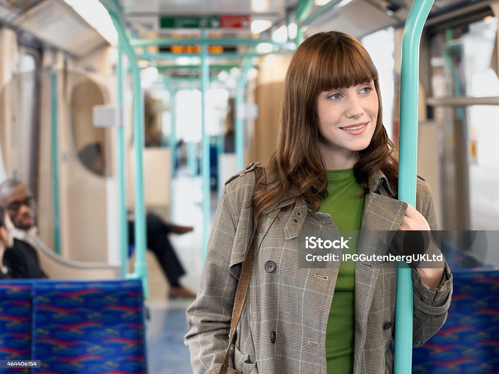 Smiling Woman Holding Bar In Commuter Train Smiling young woman standing in commuter train holding bar 2015 Stock Photo
