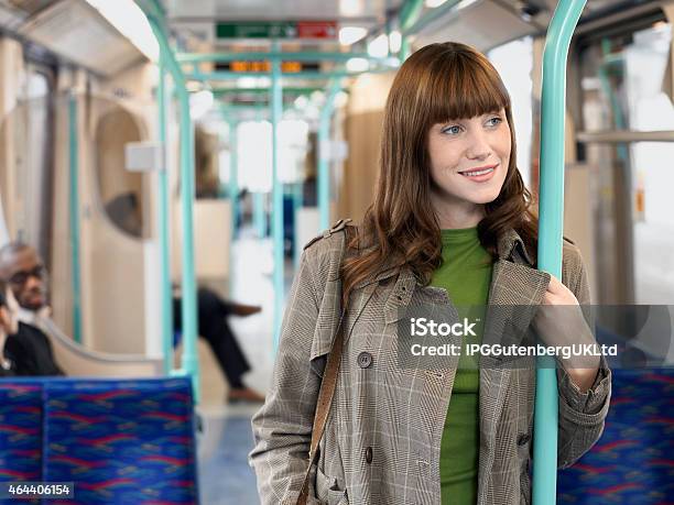 Smiling Woman Holding Bar In Commuter Train Stock Photo - Download Image Now - 2015, Adult, Brown Hair