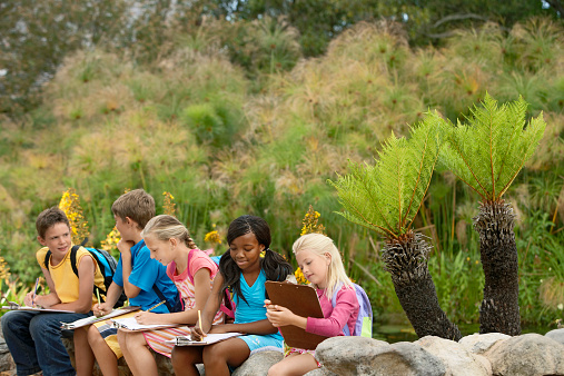 Young children preparing notes on clipboards during field trip