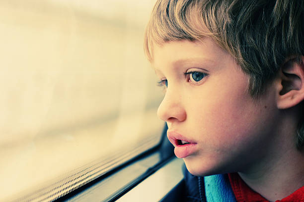istock Sad boy looking out the window of a school bus 464406322