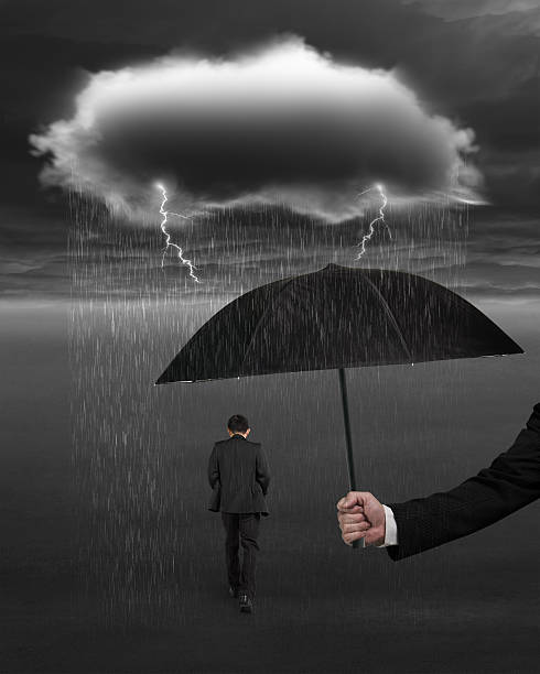 istock Hand holding umbrella protecting businessman from dark cloud rai 464412690