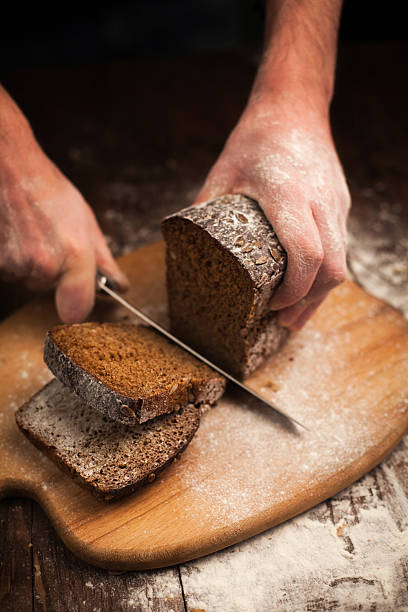 istock Male hands slicing fresh bread on table 464412774