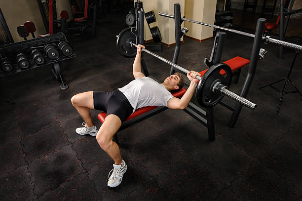 Young man doing bench press exercise at the gym handsome young man doing bench press workout in gym pectoral muscle stock pictures, royalty-free photos & images