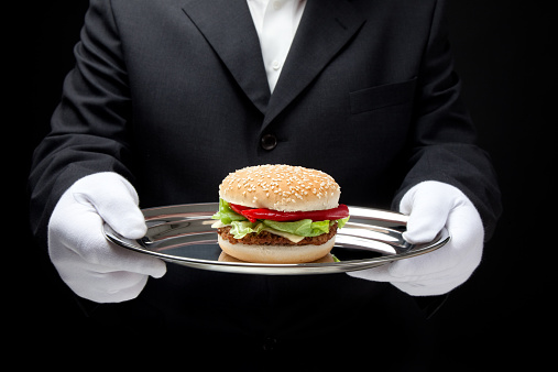 white gloved butler serving hamburger on silver tray