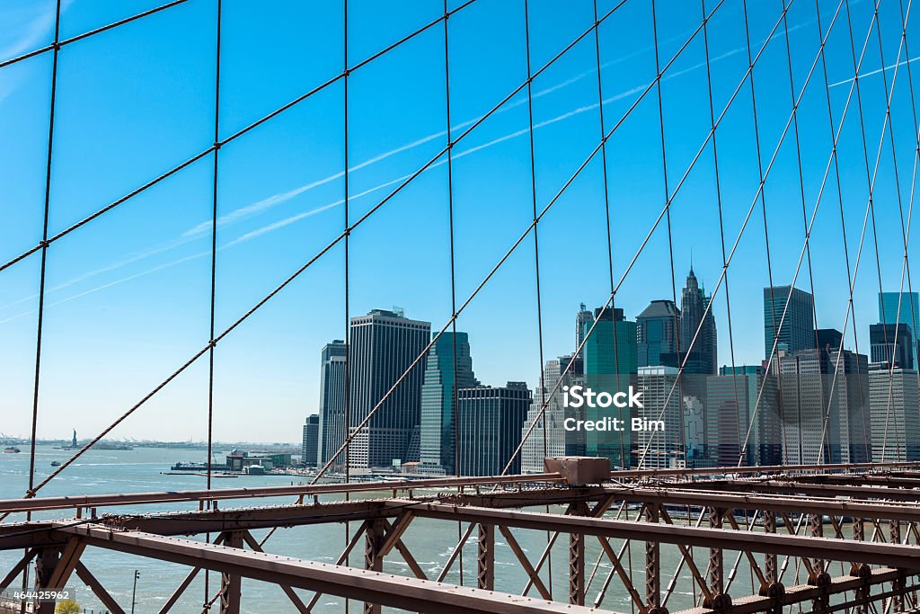 Manhattan View From Brooklyn Bridge Lower Manhattan skyline seen through cables of Brooklyn Bridge, sunny day with blue sky, New York 2015 Stock Photo