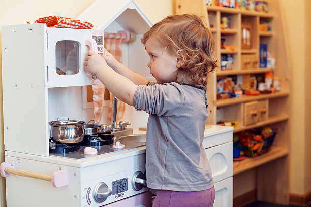 A child playing with a fake kitchen toddler girl playing toy kitchen gender stereotypes photos stock pictures, royalty-free photos & images