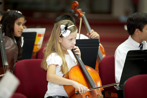 Young cellist plays in a concert with the orchestra.