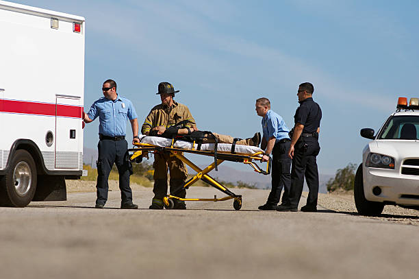 Paramedics and a firefighter pushing a person on stretcher Paramedics transporting victim on stretcher police and firemen stock pictures, royalty-free photos & images