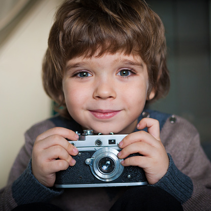 beautiful  happy smiling   little boy with a vintage camera have big eyes and long eyelashes