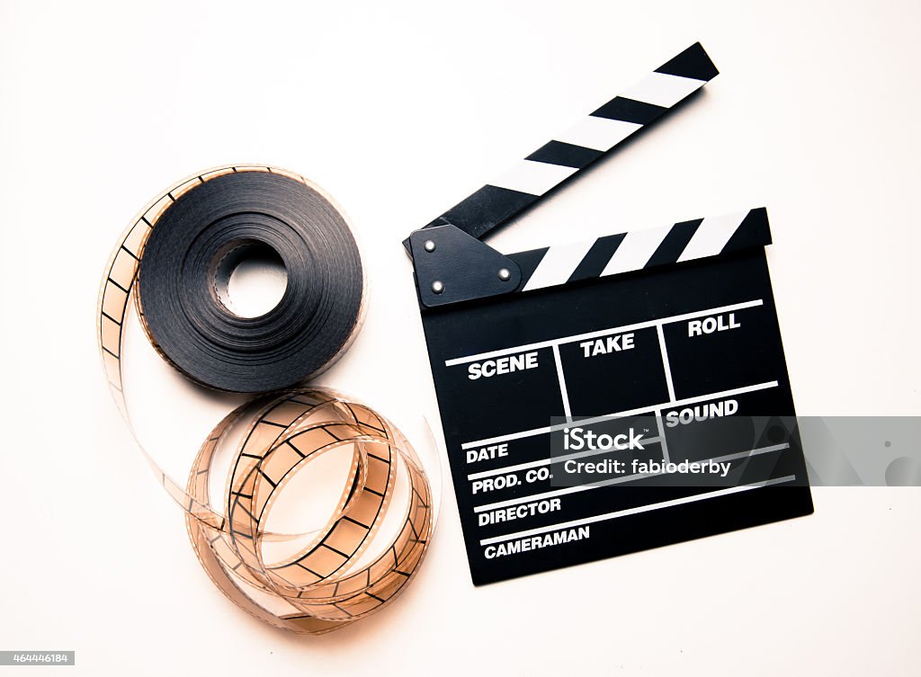 Unrolled 35mm movie reel and clapperboard in vintage color effect Unrolled 35mm movie reel and clapperboard on right side in vintage color effect 2015 Stock Photo