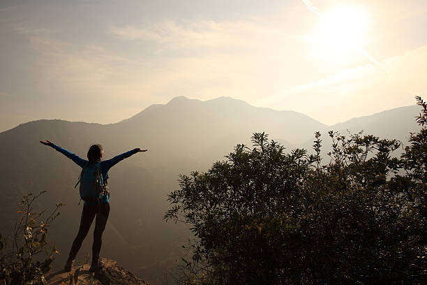 istock cheering woman hiker open arms at mountain peak 464446612