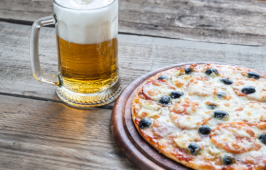 Cooked pizza with a glass of beer