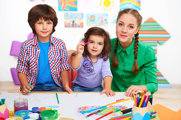 istock Teacher with children drawing and looking at camera 464448452