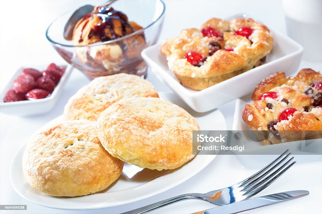 Desert pastries and profiteroles selection Pastries selection and profiteroles in glass bowl with raspberry sauce displayed in contemporary white crockery 2015 Stock Photo