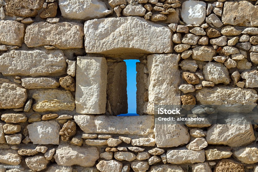 Loophole in the wall of an ancient fortress Sea over the window opening in the fortress in Greece, Heraklion. Bright sunny day outside the windows of the fortress wall 2015 Stock Photo