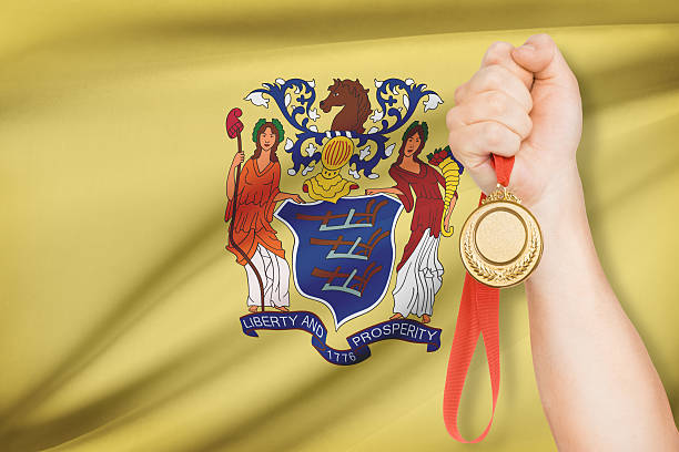 Medal in hand with flag on background - New Jersey Sportsman holding gold medal with State of New Jersey flag on background. Part of a series. jerseyan stock pictures, royalty-free photos & images