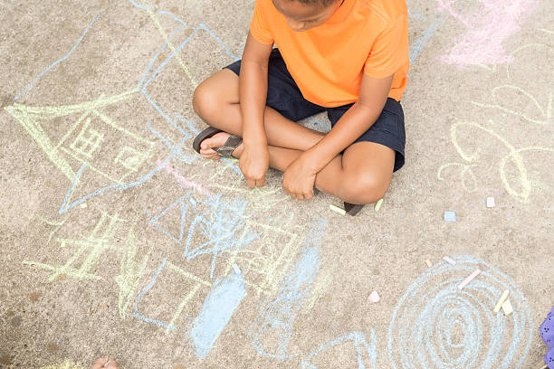 istock Children: African descent little boy playing with sidewalk chalk outside. 464474971